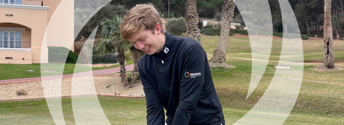 Tom-Hughes-Website Tom Hughes on the pitch in a Matrix Group branded black jumper.